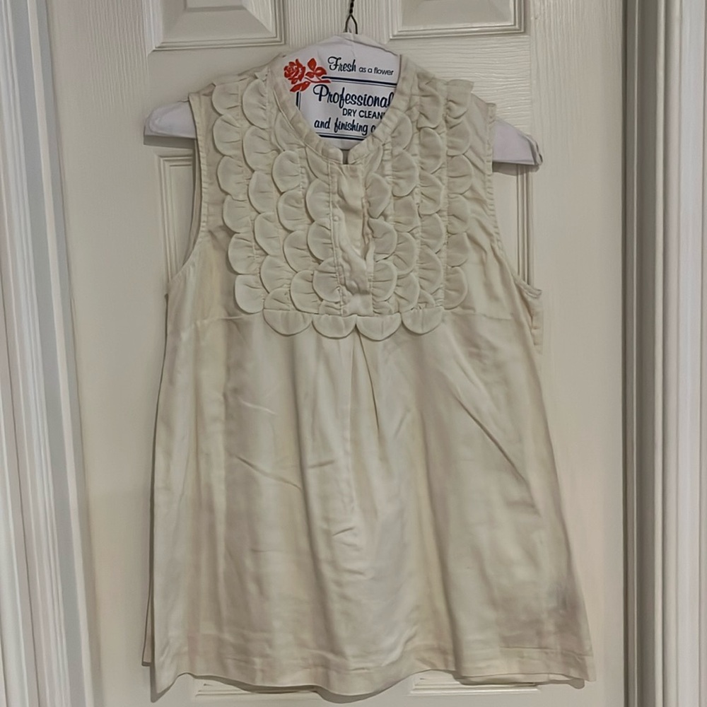 Cream sleeveless top with ruffles.